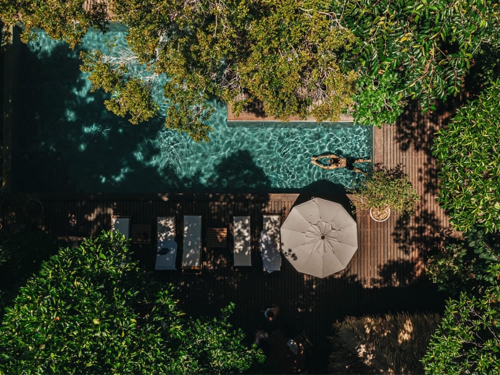 Aerial view of a swimming pool at a luxury eco-lodge nestled deep within the Amazon Rainforest vegetation, offering leisure in nature.