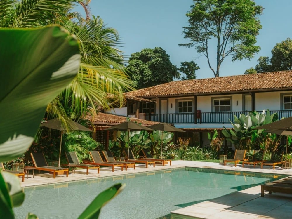 Calm water pool surrounded by lounge chairs and plants in the inner courtyard of a colonial inn.