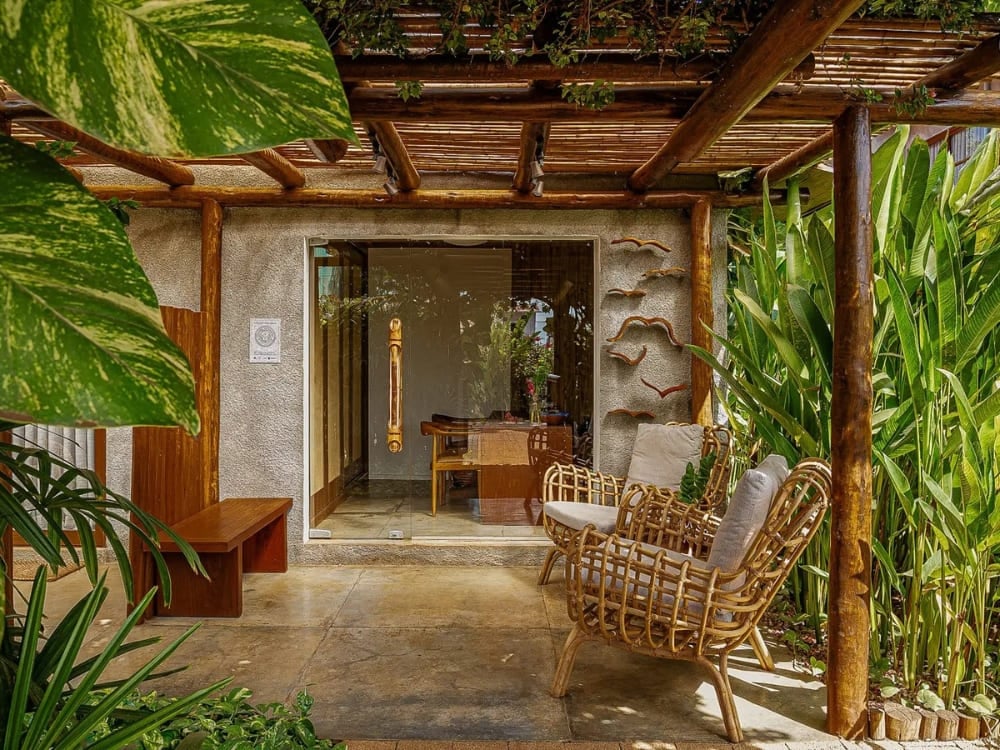 Charming suite balcony with a wooden pergola, wicker chairs, and tropical plants.