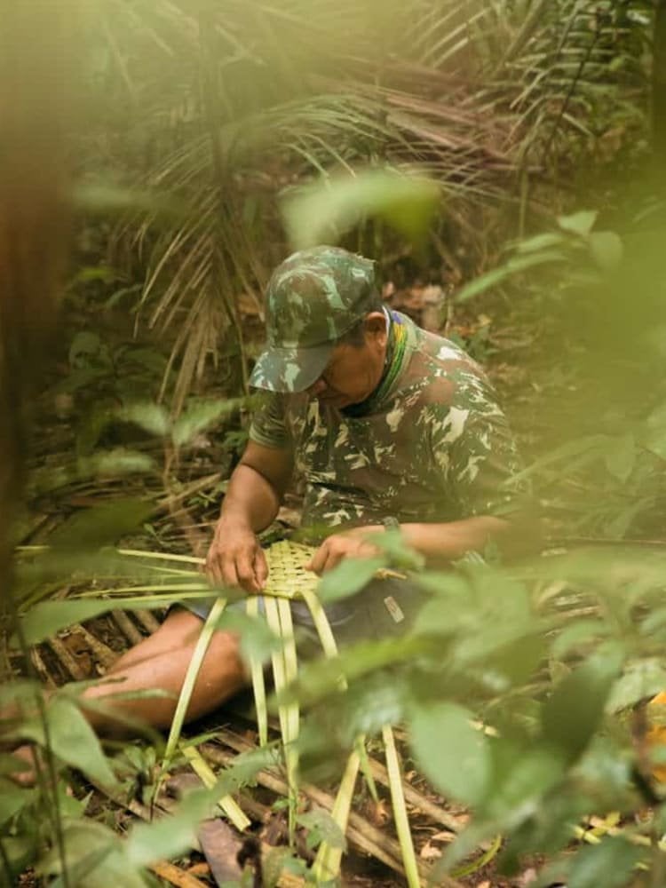 Survival guide weaving palm fronds during a jungle survival course in the Amazon