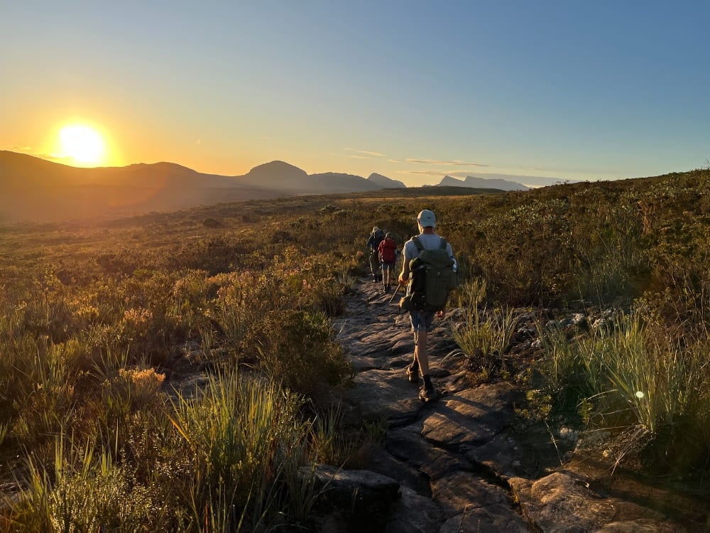 A group hiking a stone path at sunrise on the Vale do Pati trek in Chapada Diamantina, Brazil.