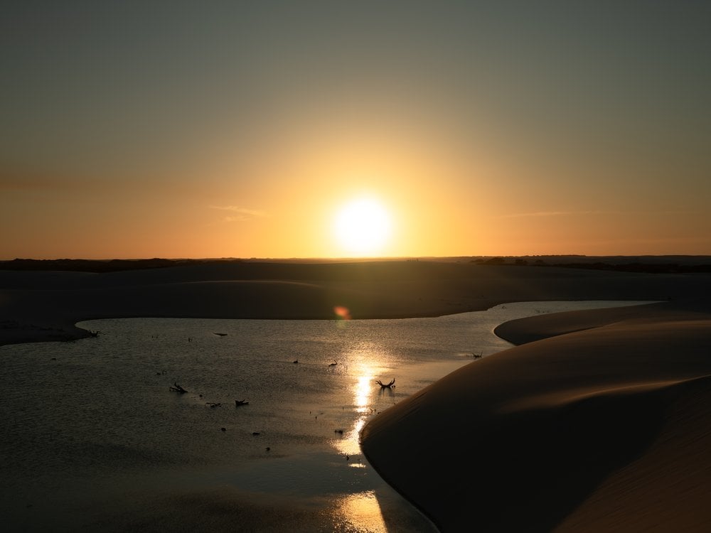 Sunset over a rainwater lagoon between the white dunes of Lençóis Maranhenses