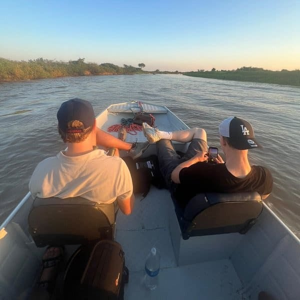 Michael's sons on a small boat cruising a Pantanal river at sunset