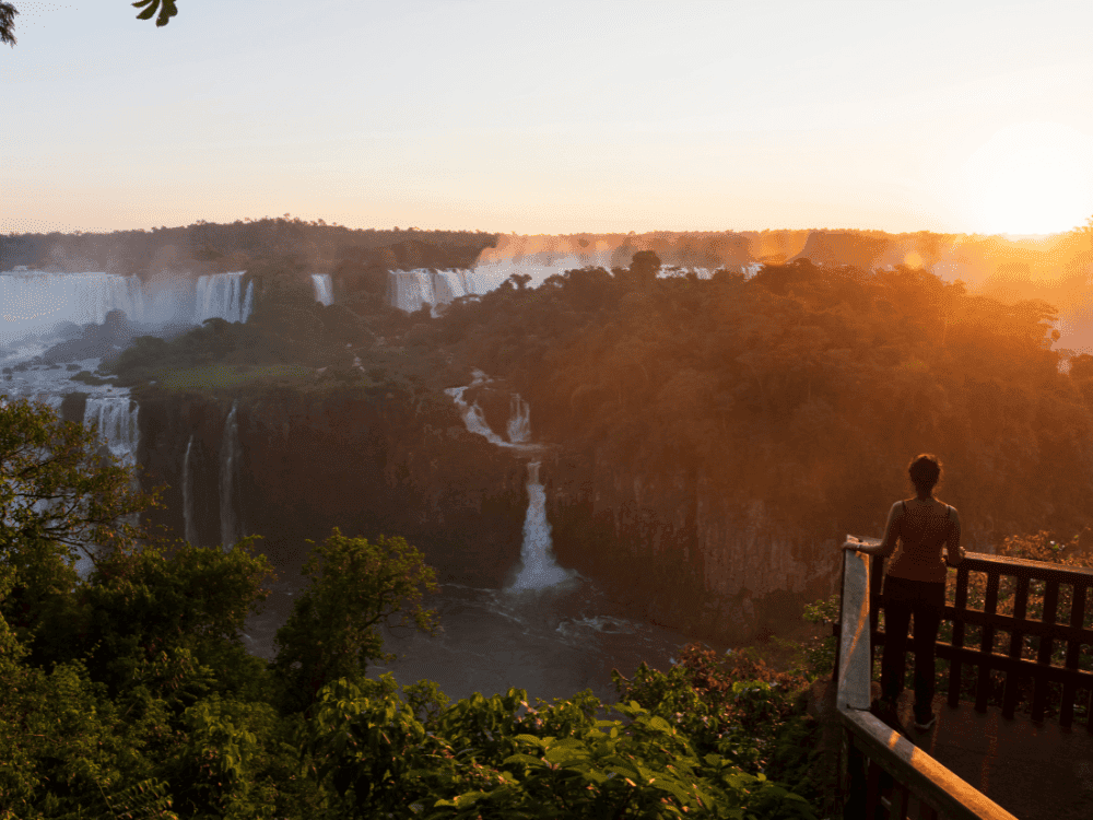 Traveler watching the sunset over Iguazu Falls from a viewpoint