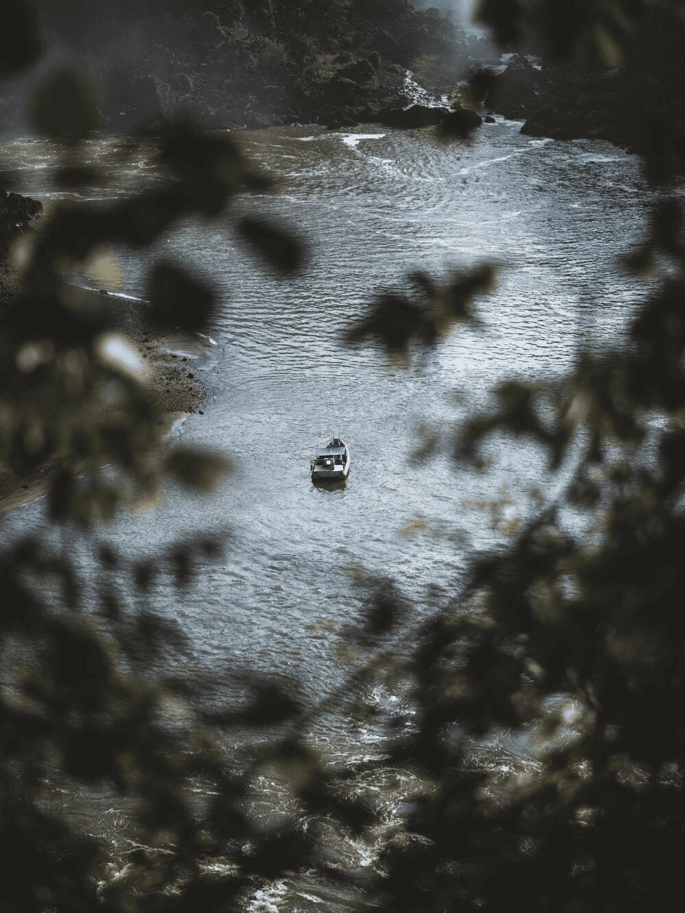 Small boat on the Iguazu River seen from above through the forest leaves