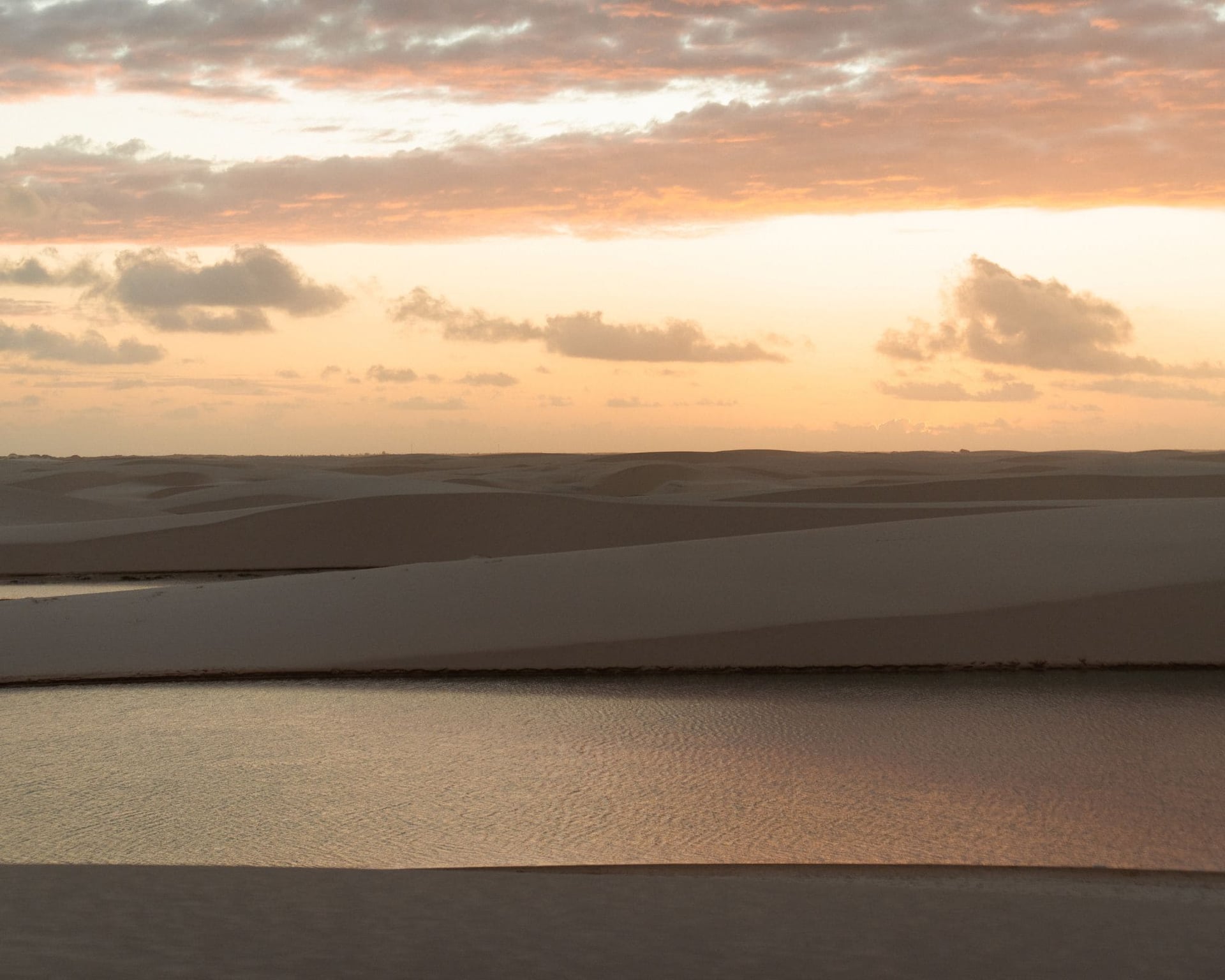Pink sunset sky over the white sand dunes and a rainwater lagoon in Lençóis Maranhenses