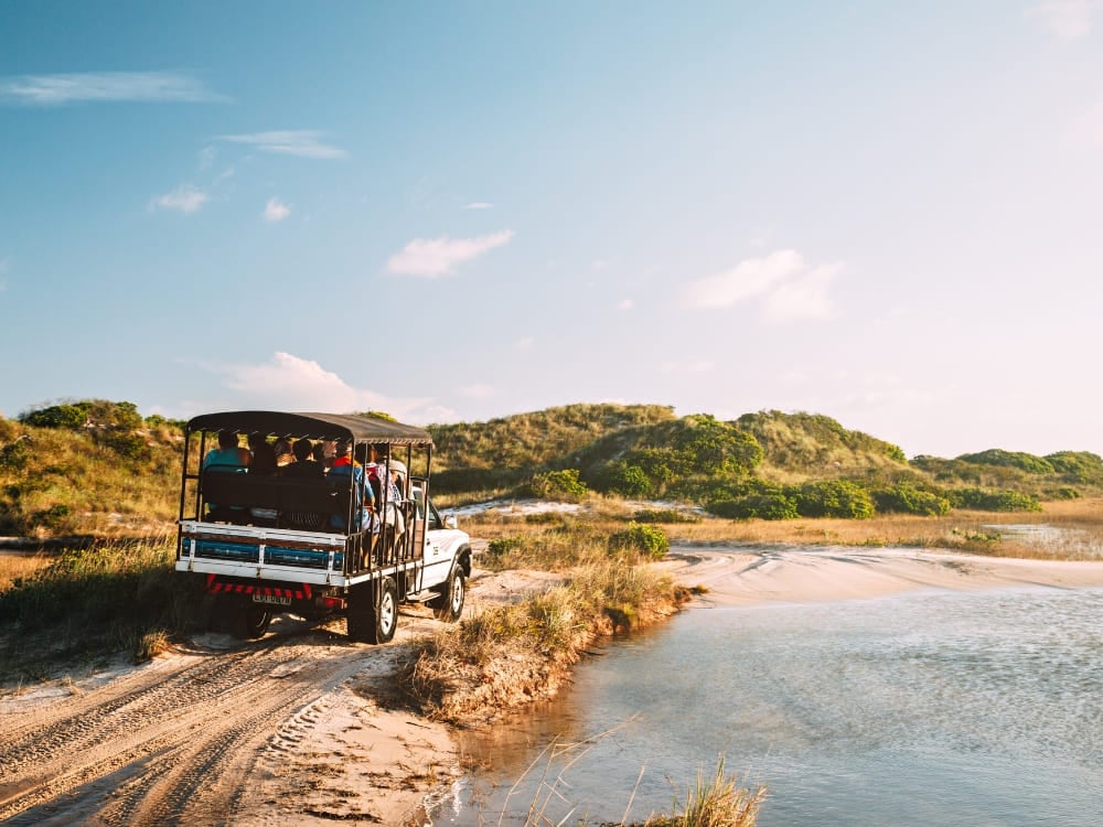 A 4x4 vehicle carries tourists along a sandy path, offering a ride into the Lençóis Maranhenses National Park. A 4x4 vehicle carries tourists along a sandy path, offering a ride into the Lençóis Maranhenses National Park.
