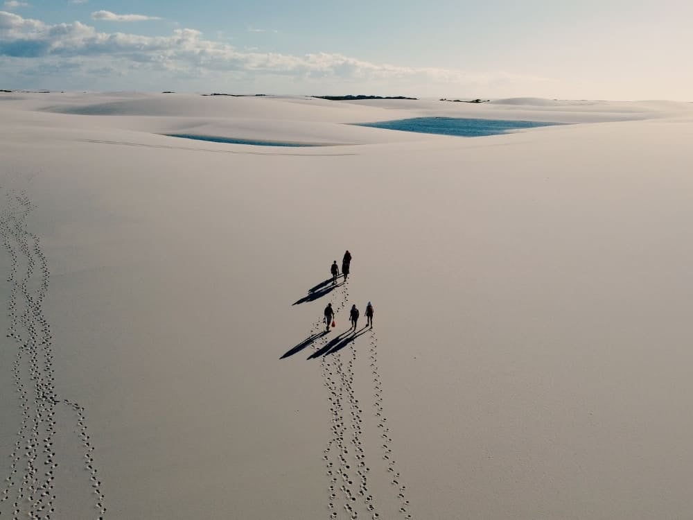 A group of people casts long shadows while exploring the sand dunes in the primitive zone of Lençóis Maranhenses. A group of people casts long shadows while exploring the sand dunes in the primitive zone of Lençóis Maranhenses.