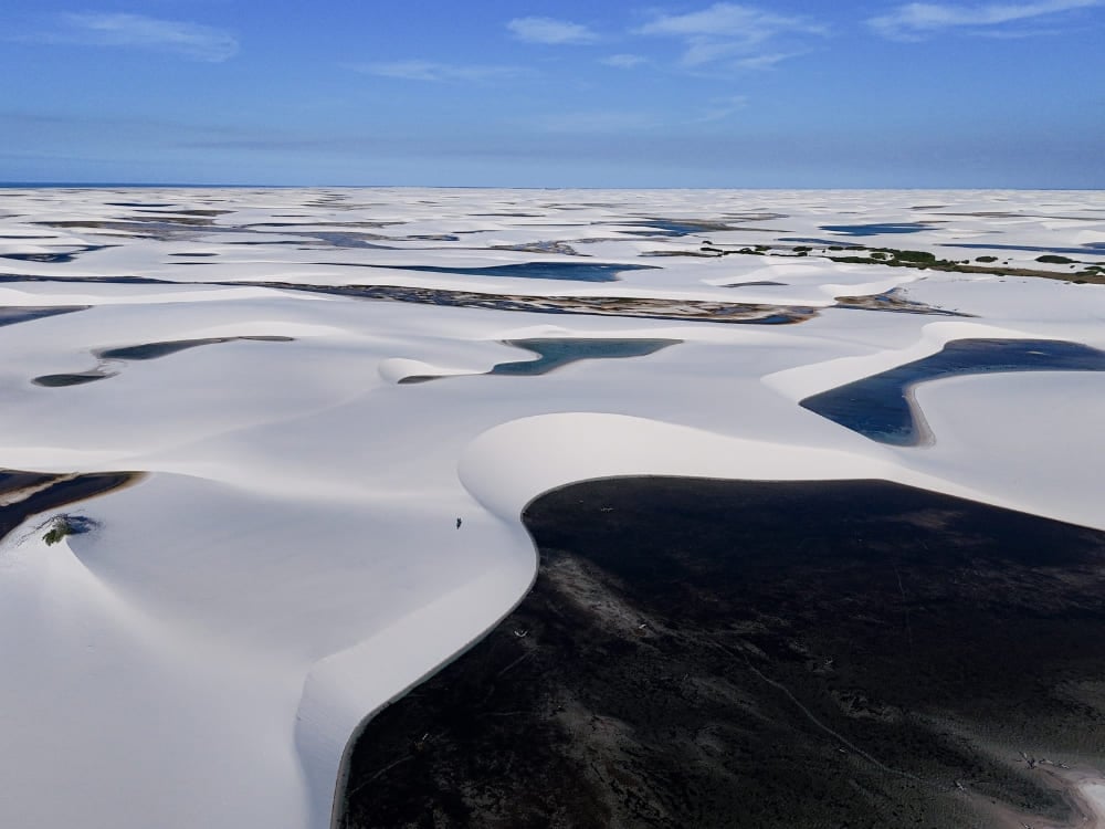A wide landscape shows thousands of rainwater lagoons interspersed among the white sand dunes. A wide landscape shows thousands of rainwater lagoons interspersed among the white sand dunes.
