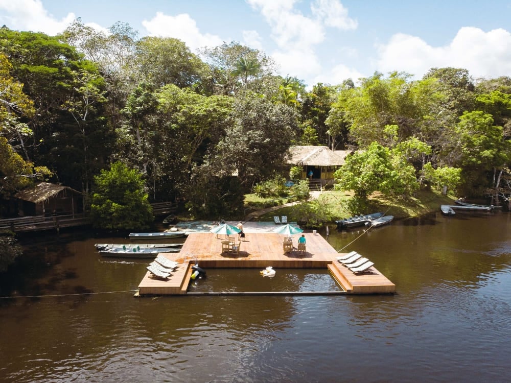 Aerial view of Dolphin Lodge showing its floating deck, boats, and chalets surrounded by the Amazon forest. Aerial view of Dolphin Lodge showing its floating deck, boats, and chalets surrounded by the Amazon forest.