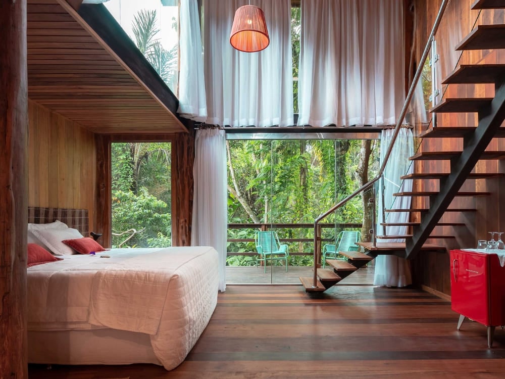 A luxury room with a large glass window facing the forest at Mirante do Gavião in the Amazon rainforest. A luxury room with a large glass window facing the forest at Mirante do Gavião in the Amazon rainforest.