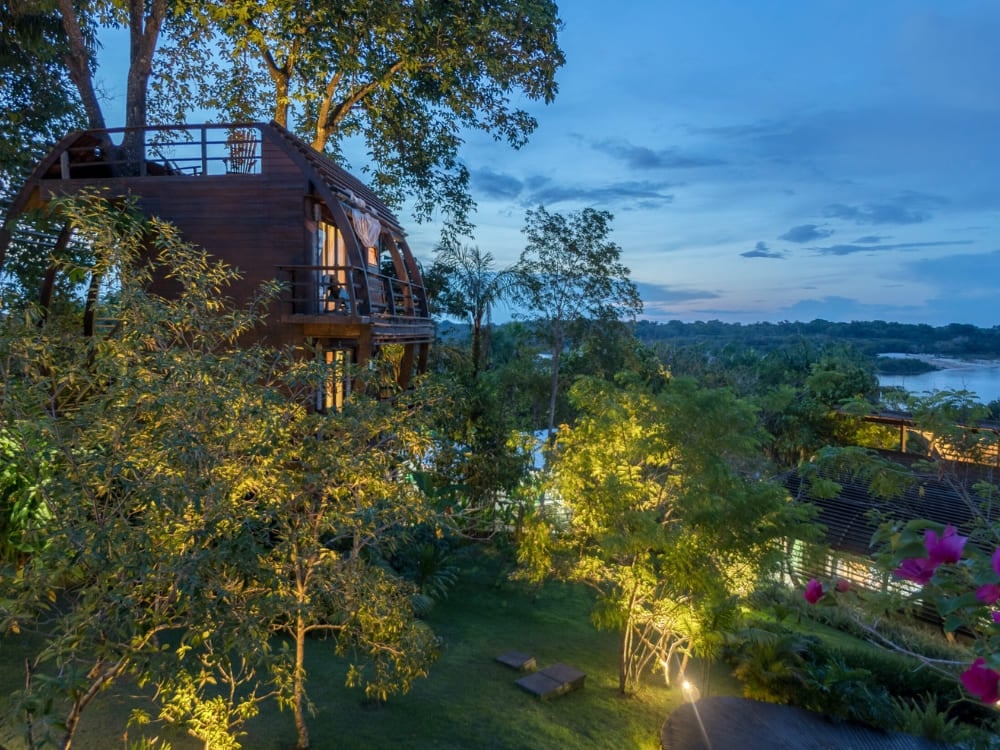 The unique wooden architecture of Mirante do Gavião lodge illuminated at dusk, representing one of the best Amazon jungle lodges in Brazil. The unique wooden architecture of Mirante do Gavião lodge illuminated at dusk, representing one of the best Amazon jungle lodges in Brazil.