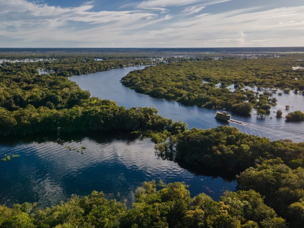 Aerial view of a winding blue river flowing through the lush green Amazon Rainforest near Manaus. Aerial view of a winding blue river flowing through the lush green Amazon Rainforest near Manaus.