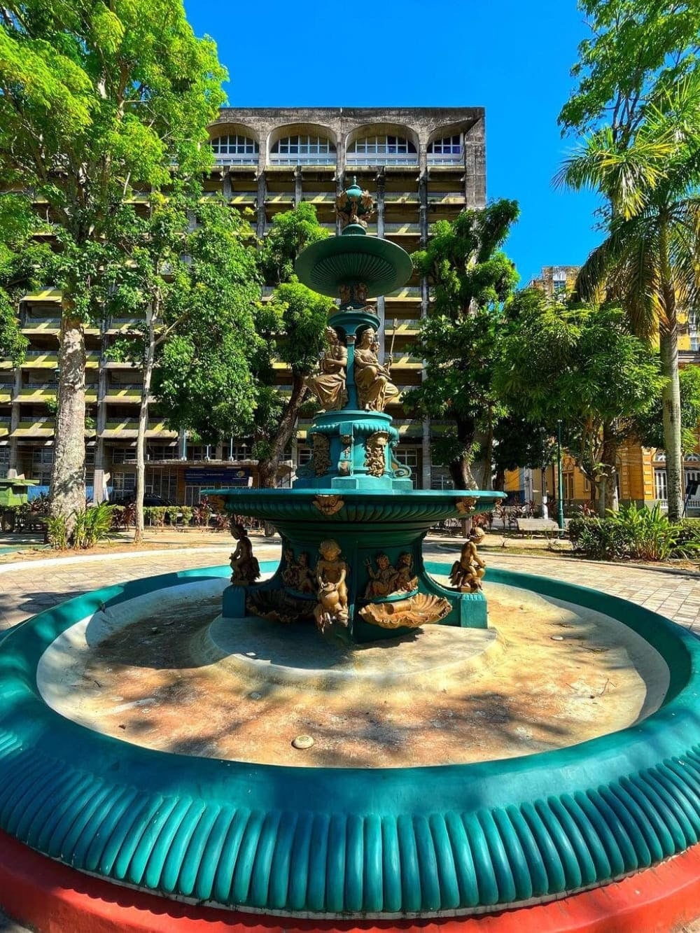 Green iron fountain located in a public square within the historic center of Manaus surrounded by trees. Green iron fountain located in a public square within the historic center of Manaus surrounded by trees.