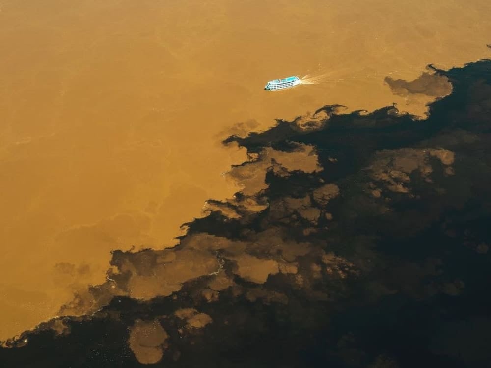 Aerial view showing the distinct dividing line where the black Rio Negro meets the brown Solimões River. Aerial view showing the distinct dividing line where the black Rio Negro meets the brown Solimões River.