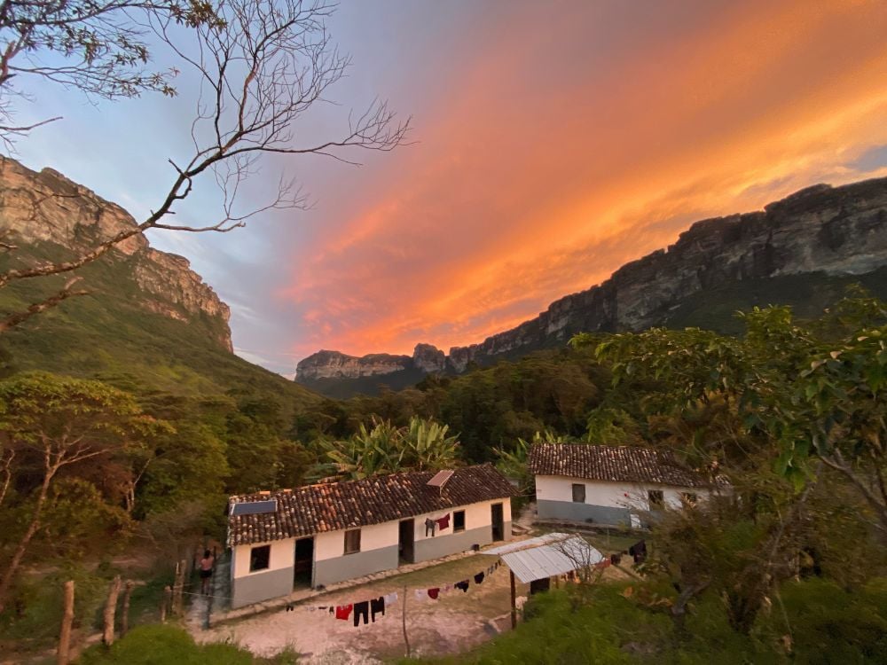 Traditional white houses with tiled roofs nestled among the trees in the Pati Valley under a vibrant orange sunset sky. Traditional white houses with tiled roofs nestled among the trees in the Pati Valley under a vibrant orange sunset sky.