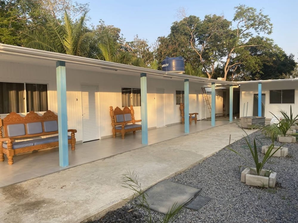 The exterior courtyard of Dona Onça lodge shows rustic accommodations with wooden benches in Porto Jofre. The exterior courtyard of Dona Onça lodge shows rustic accommodations with wooden benches in Porto Jofre.