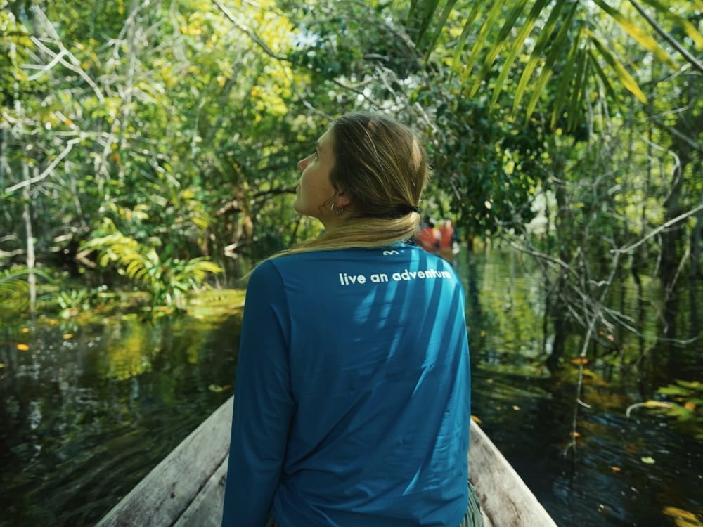 Tourist navigating a canoe through the green canopy of the flooded Amazon rainforest looking up at the trees. Tourist navigating a canoe through the green canopy of the flooded Amazon rainforest looking up at the trees.