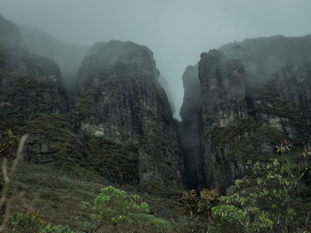 Imposing, steep rock faces partially covered by thick mist at Pico da Neblina National Park. Imposing, steep rock faces partially covered by thick mist at Pico da Neblina National Park.