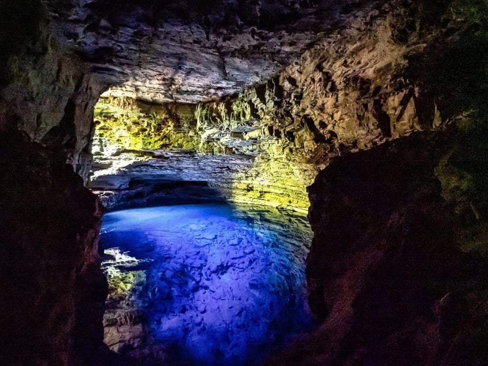 A bright ray of sunlight illuminates the crystal-clear blue water inside the underground limestone cave of Poço Encantado. A bright ray of sunlight illuminates the crystal-clear blue water inside the underground limestone cave of Poço Encantado.