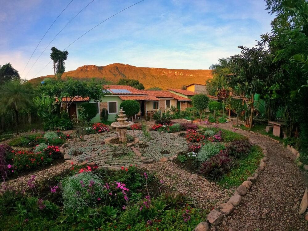 A well-kept circular garden with a stone fountain at a peaceful retreat, framed by green mountains in Chapada Diamantina. A well-kept circular garden with a stone fountain at a peaceful retreat, framed by green mountains in Chapada Diamantina.