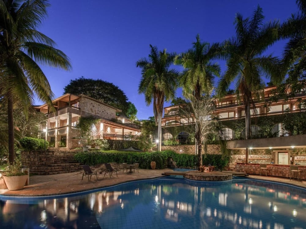 Illuminated swimming pool and tropical palm trees at night at Hotel Canto das Águas in Lençóis. Illuminated swimming pool and tropical palm trees at night at Hotel Canto das Águas in Lençóis.