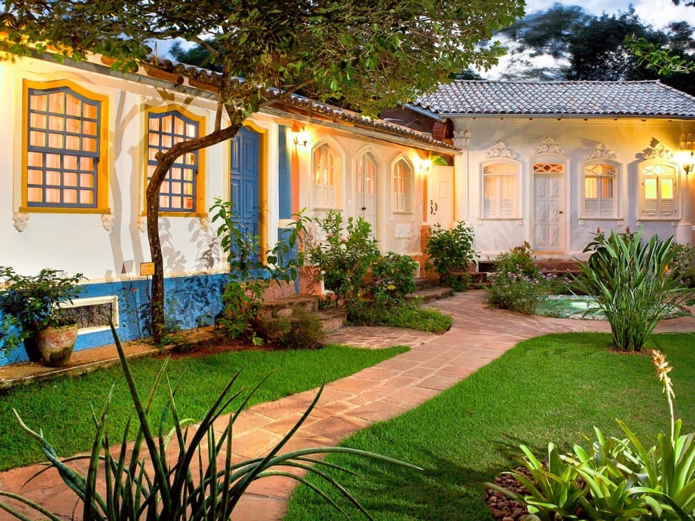 Colonial-style courtyard of Pousada Vila Serrano in Lençóis featuring blue and white walls and lush green gardens. Colonial-style courtyard of Pousada Vila Serrano in Lençóis featuring blue and white walls and lush green gardens.