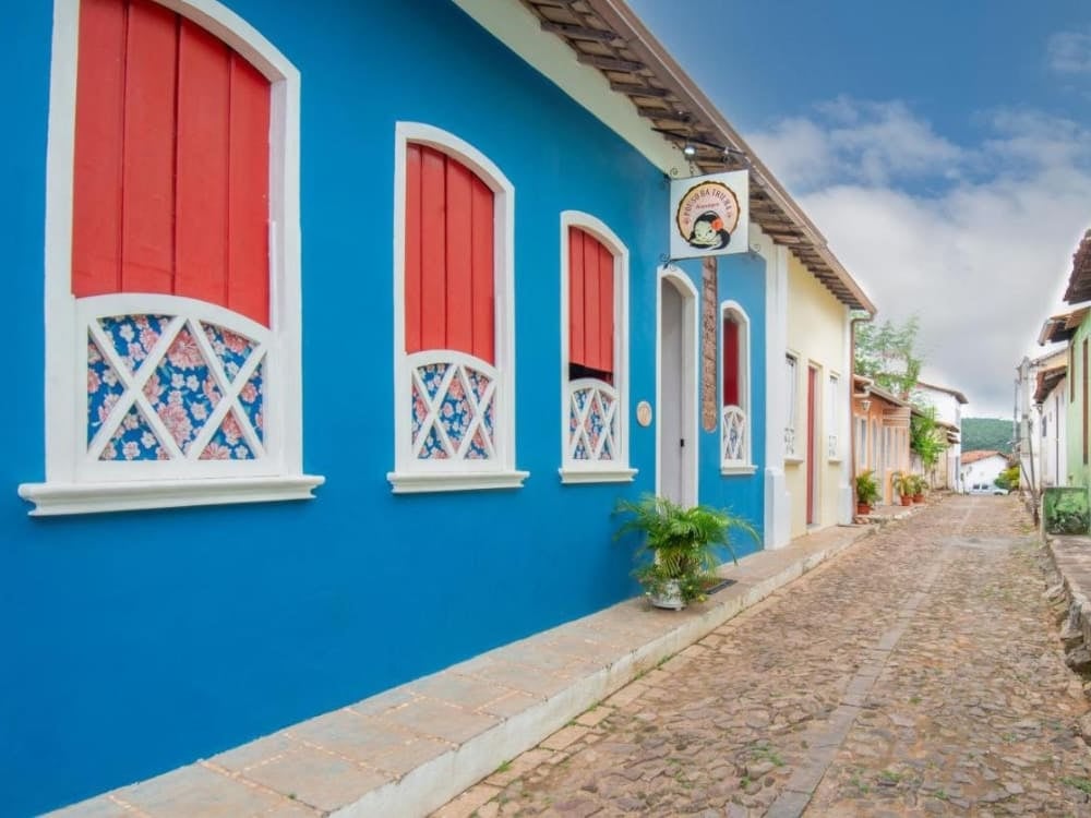 Bright blue facade with white and red window frames of Pousada Alto do Cajueiro on a cobblestone street in Lençóis. Bright blue facade with white and red window frames of Pousada Alto do Cajueiro on a cobblestone street in Lençóis.