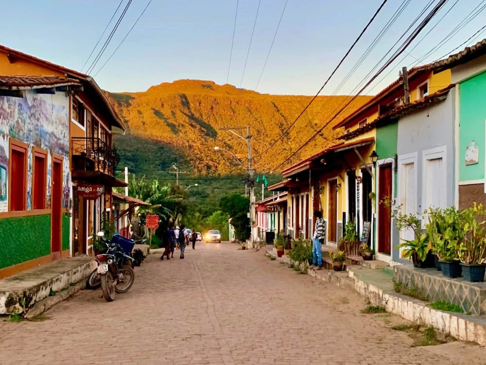 Colorful houses lining the peaceful main street of Vale do Capão with a massive mountain glowing at sunset. Colorful houses lining the peaceful main street of Vale do Capão with a massive mountain glowing at sunset.