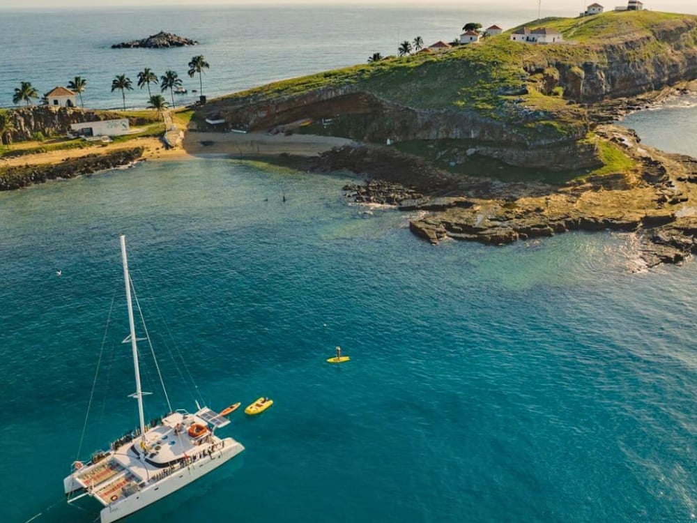 Aerial view of a white catamaran anchored in crystal clear waters next to a green island in the Abrolhos archipelago. Aerial view of a white catamaran anchored in crystal clear waters next to a green island in the Abrolhos archipelago.