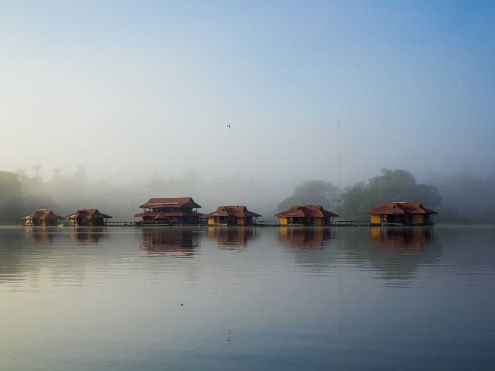 Uakari Lodge floating inn made of wooden cabins on the calm waters of Lake Mamirauá with mist in the background. Uakari Lodge floating inn made of wooden cabins on the calm waters of Lake Mamirauá with mist in the background.