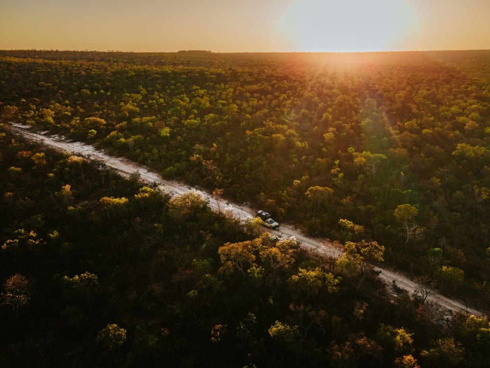 An off-road vehicle driving on a dirt road through the vast Cerrado plains illuminated by the golden sunset light. An off-road vehicle driving on a dirt road through the vast Cerrado plains illuminated by the golden sunset light.