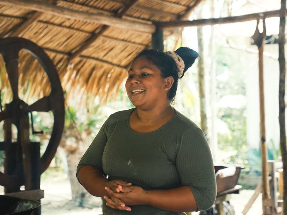 Smiling woman from an Amazon riverside community standing under a traditional thatched roof. Smiling woman from an Amazon riverside community standing under a traditional thatched roof.