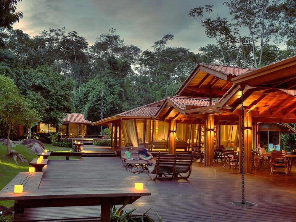 A wooden deck illuminated by small lights at dusk, surrounded by the lush tropical vegetation of the rainforest. A wooden deck illuminated by small lights at dusk, surrounded by the lush tropical vegetation of the rainforest.