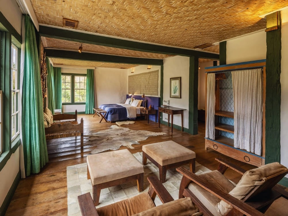 Spacious rustic bedroom with a large bed, wooden floors, and green accents at Ibiti Project. Spacious rustic bedroom with a large bed, wooden floors, and green accents at Ibiti Project.