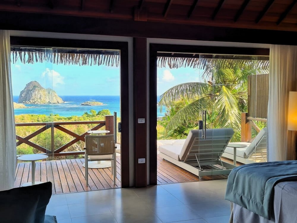 Open balcony doors revealing a lounge chair and stunning ocean views in Fernando de Noronha. Open balcony doors revealing a lounge chair and stunning ocean views in Fernando de Noronha.