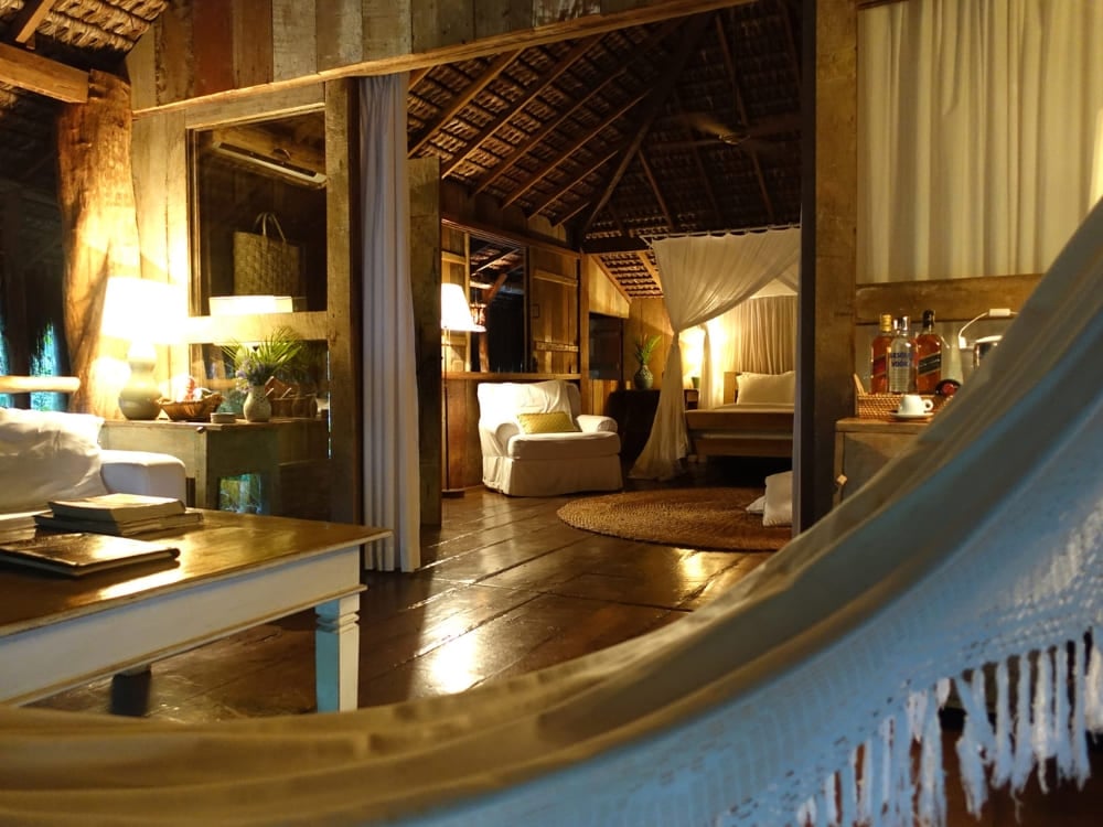 View from a hammock looking into a warmly lit rustic suite with wooden floors at UXUA. View from a hammock looking into a warmly lit rustic suite with wooden floors at UXUA.