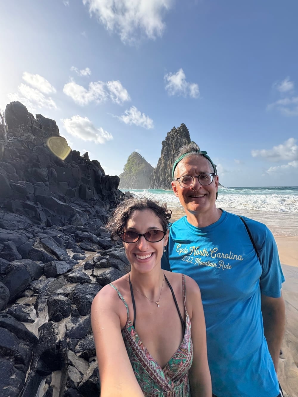 Father and daughter taking a selfie on a rocky beach with the Morro Dois Irmãos rock formations and the ocean in the background. Father and daughter taking a selfie on a rocky beach with the Morro Dois Irmãos rock formations and the ocean in the background.