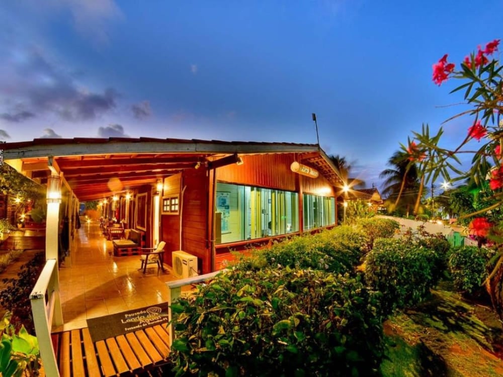Illuminated rustic pousada exterior at dusk with tropical flowers and a welcoming atmosphere in Fernando de Noronha. Illuminated rustic pousada exterior at dusk with tropical flowers and a welcoming atmosphere in Fernando de Noronha.