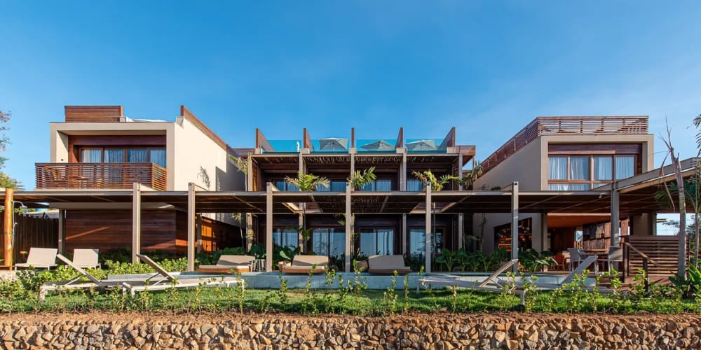 Modern exterior of Pousada Mirante featuring a long rectangular swimming pool, sun loungers, and wooden pergolas, highlighting premium hotels in Fernando de Noronha. Modern exterior of Pousada Mirante featuring a long rectangular swimming pool, sun loungers, and wooden pergolas, highlighting premium hotels in Fernando de Noronha.