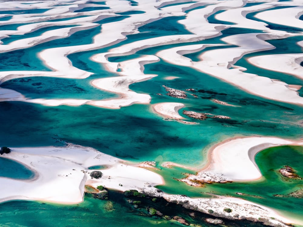 Aerial view of the white sand dunes and green rainwater lagoons in Lençóis Maranhenses National Park. Aerial view of the white sand dunes and green rainwater lagoons in Lençóis Maranhenses National Park.