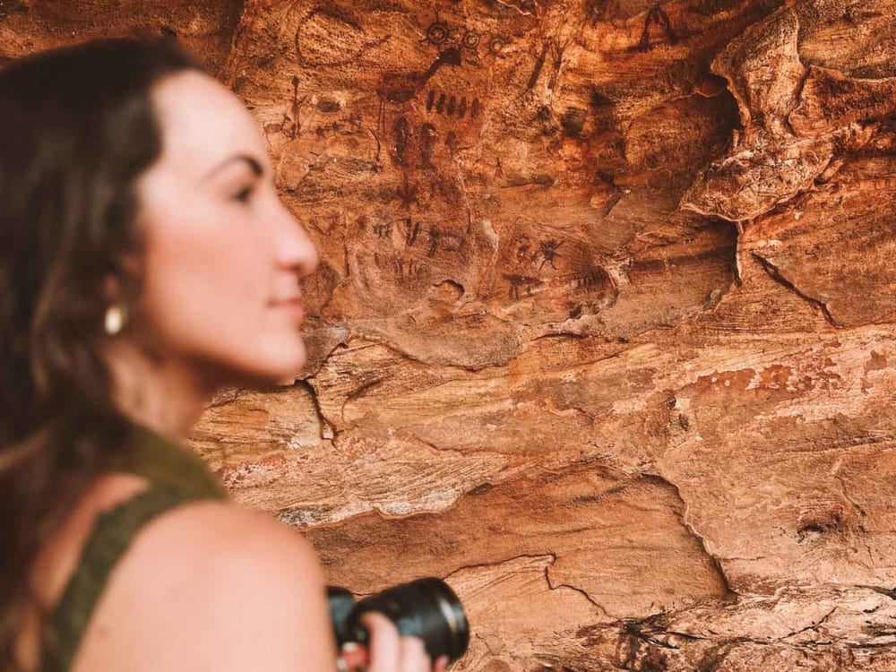 Woman viewing ancient cave paintings on a rock wall inside Serra da Capivara National Park. Woman viewing ancient cave paintings on a rock wall inside Serra da Capivara National Park.