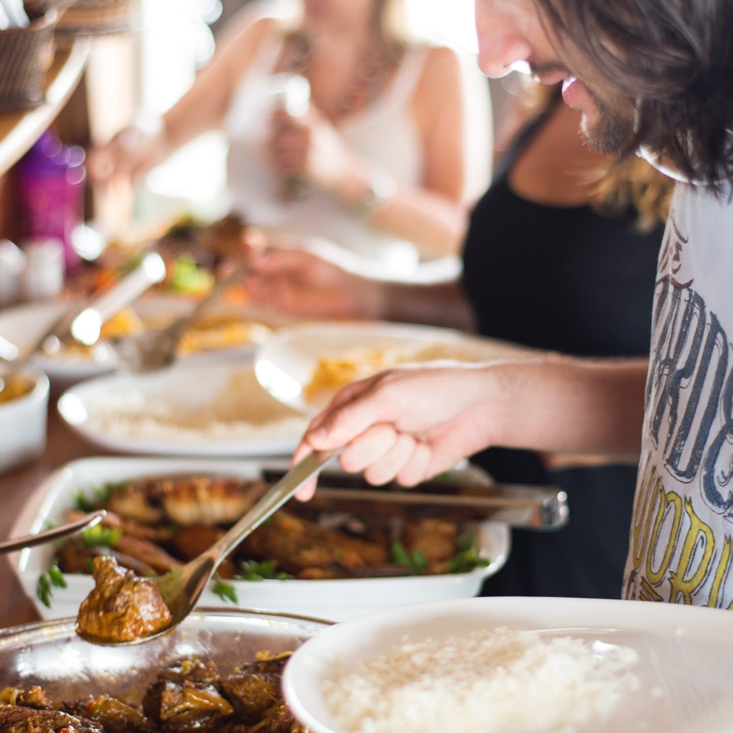 Portions are generous, the river is right outside, and nobody is counting seconds. Travelers serving themselves from large shared dishes of braised meat and grilled fish at a buffet lunch on an amazon river cruise in brazil