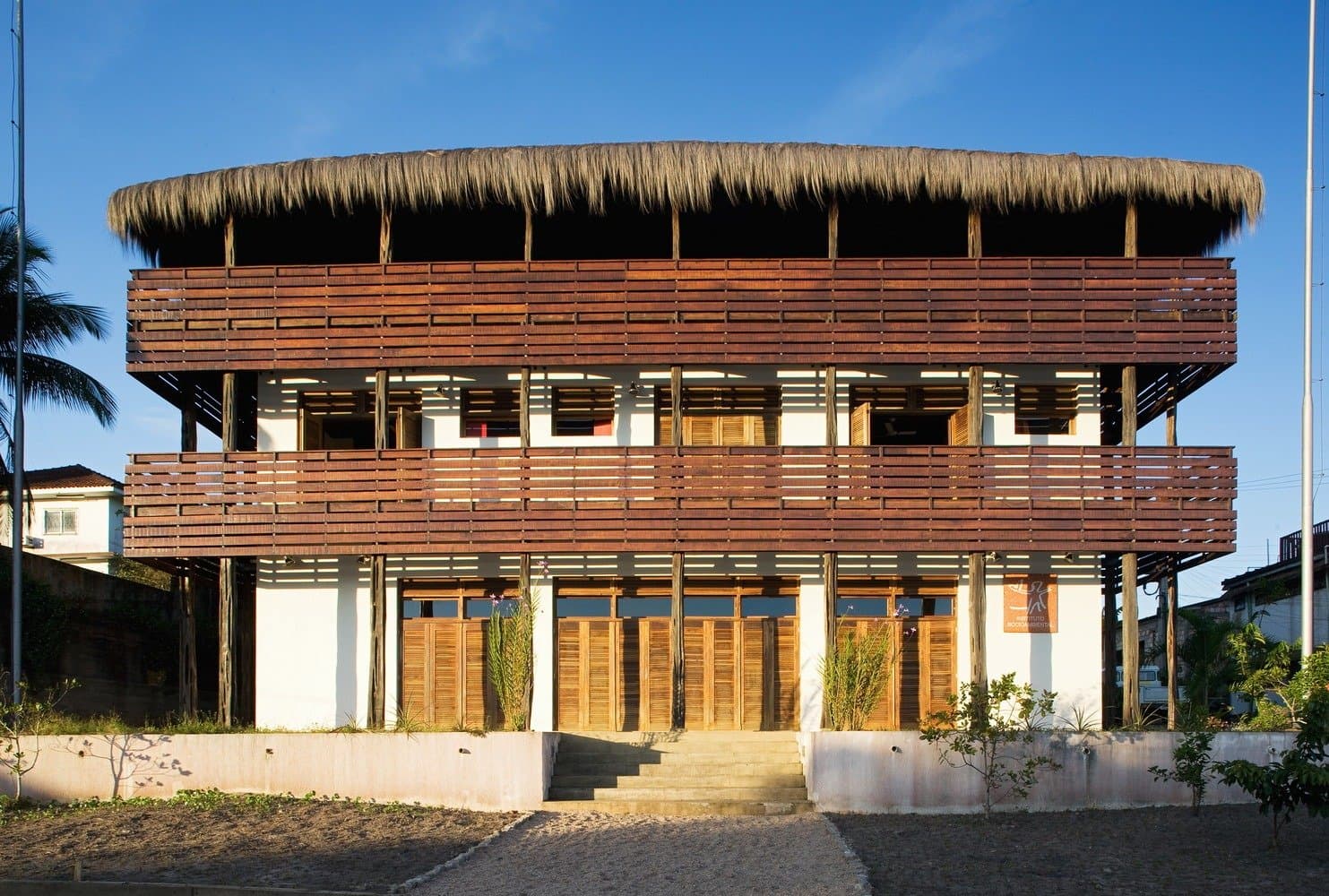 Your last comfortable night before the forest has its say. Three-storey tropical building with horizontal wooden slatted balconies and a wide circular thatched roof, serving as the guesthouse base for the Pico da Neblina Expedition in São Gabriel da Cachoeira