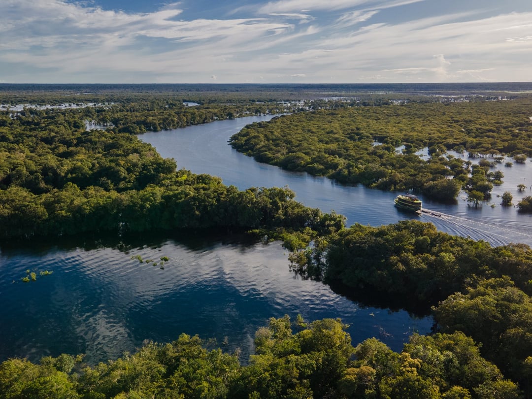 An aerial view of a riverboat winding through the flooded forest and river channels of the Brazilian Amazon. An aerial view of a riverboat winding through the flooded forest and river channels of the Brazilian Amazon.