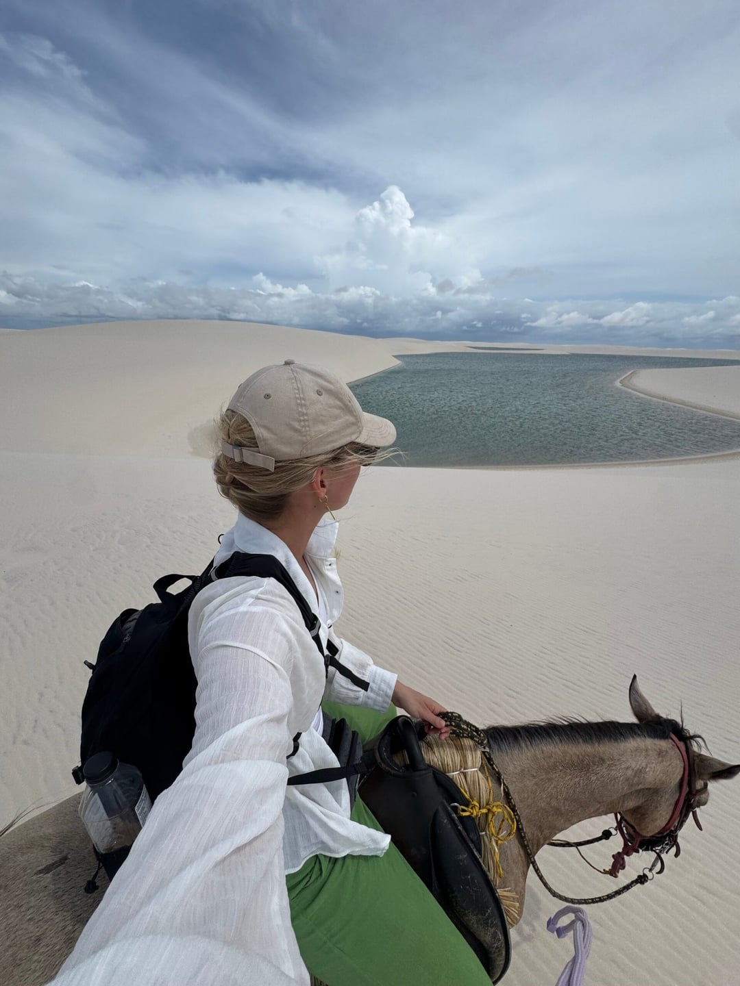 A rider stands beside her horse on the dunes, looking out over a lagoon in the roadless interior of Lençóis Maranhenses. A rider stands beside her horse on the dunes, looking out over a lagoon in the roadless interior of Lençóis Maranhenses.