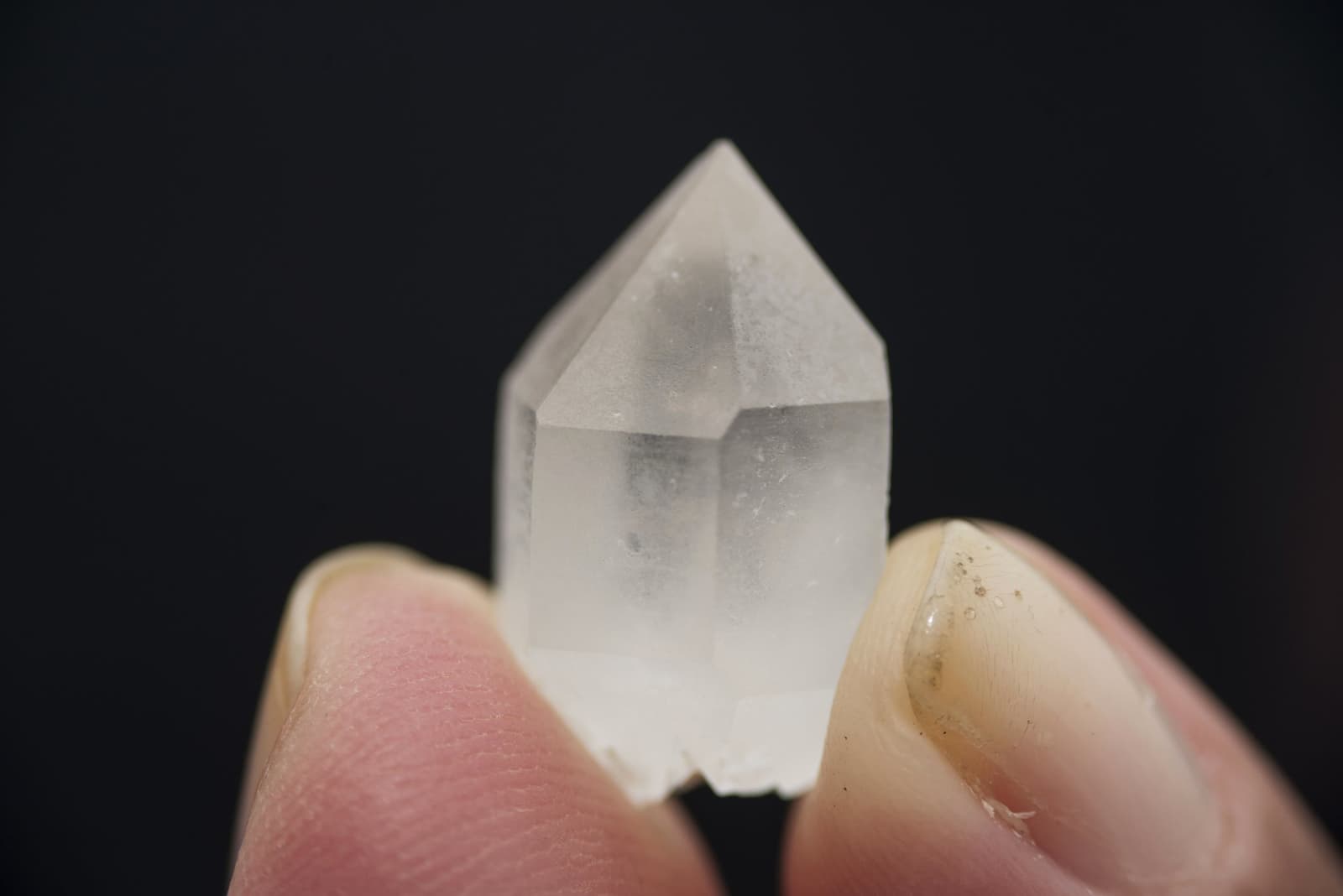 The tepui gives up its secrets one small crystal at a time. A small clear quartz crystal point held between two fingers against a black background, found during the Mount Roraima trek through the Valley of Crystals
