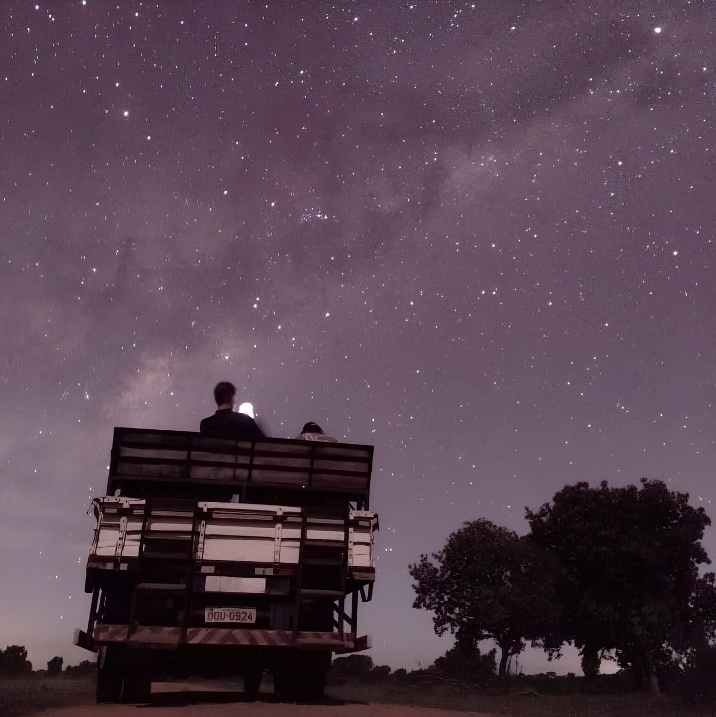Some offices have better ceilings than others. Two travelers sitting on the back of an open safari vehicle beneath a vast star-filled sky and visible Milky Way on a Pantanal Bonito tour night safari