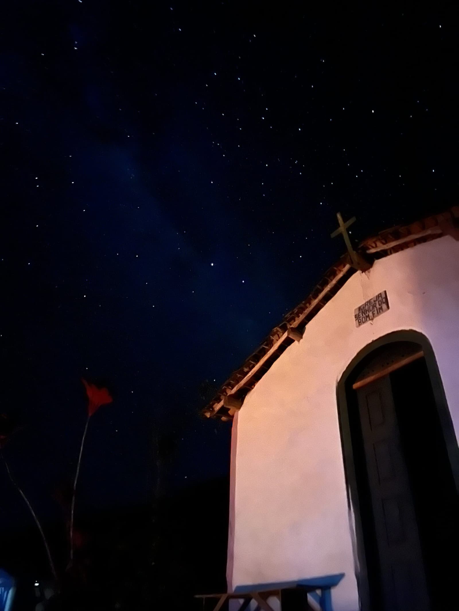 Old walls, older stars, the Pati Valley keeps quiet hours. A whitewashed colonial chapel signed 'Igreja Senhor do Bonfim' glows under a star-filled night sky on the Pati Valley hike, with a rooftop cross silhouetted against the Milky Way