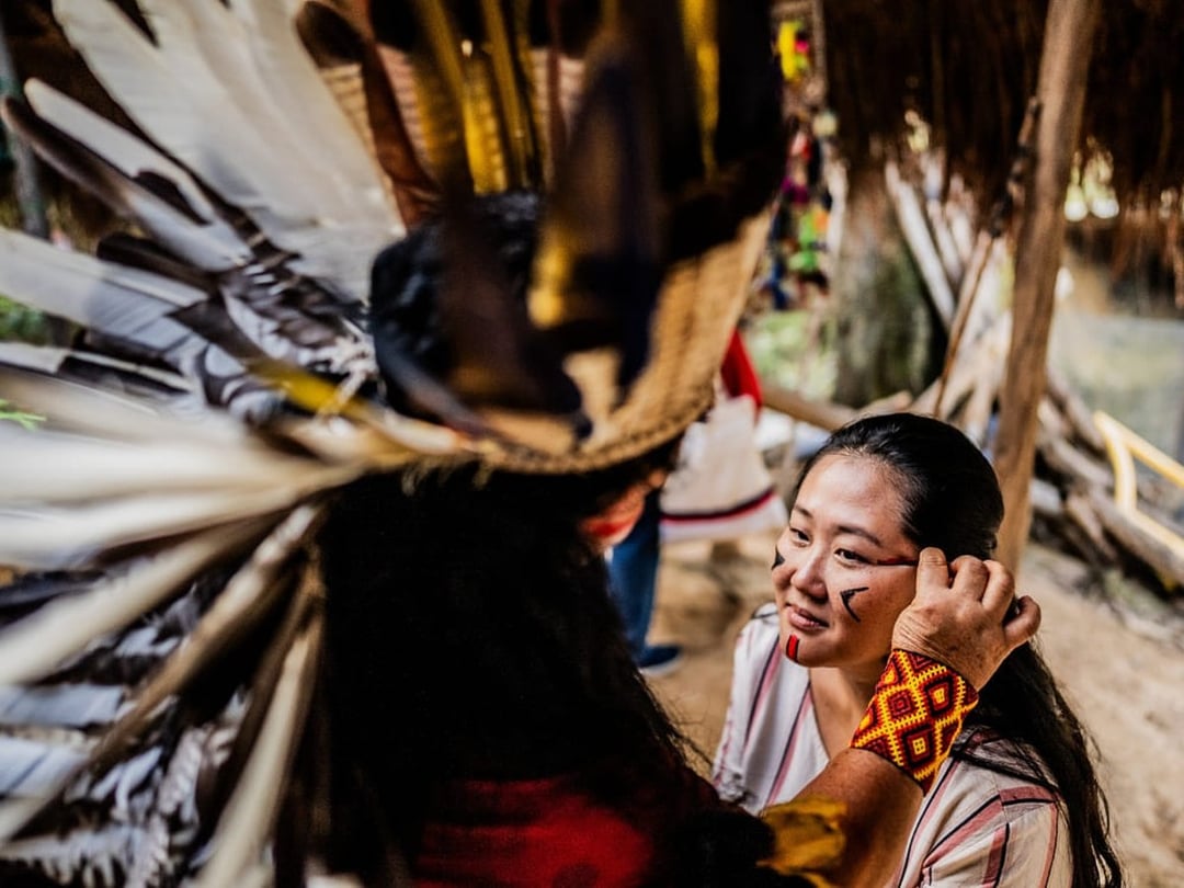 Traveler receiving traditional Indigenous face paint during a community visit in the Amazon Traveler receiving traditional Indigenous face paint during a community visit in the Amazon